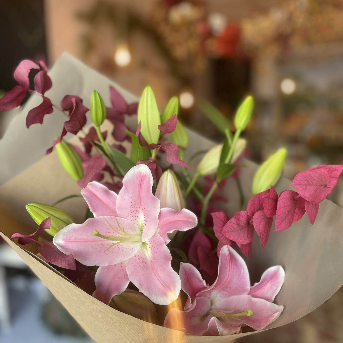 Bouquet de lys roses et feuillages pourpres dans son papier kraft, création Un Jardin en Ville, fleuriste à Bordeaux